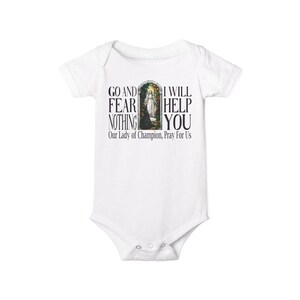 May include: A white short-sleeved baby bodysuit featuring a graphic print of a religious figure in an archway. The text reads: GO AND FEAR NOTHING I WILL HELP YOU Our Lady of Champion, Pray For Us. The garment has a crew neckline and snap closures.