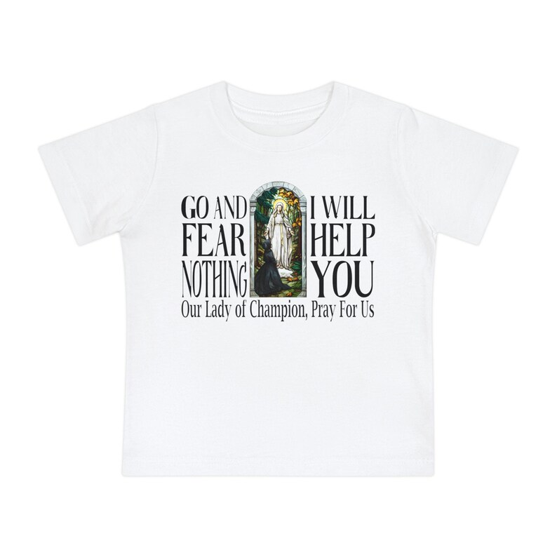 May include: A white short-sleeved t-shirt featuring a central graphic of a stained-glass window depicting a religious figure. The text reads: GO AND FEAR NOTHING I WILL HELP YOU and Our Lady of Champion, Pray For Us in black lettering.
