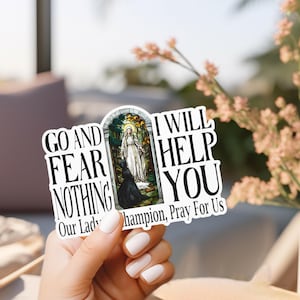 May include: A die-cut sticker featuring a central stained-glass style illustration of a figure in white robes standing before a kneeling person. The text reads: GO AND FEAR NOTHING I WILL HELP YOU Our Lady of Champion, Pray For Us in black font.