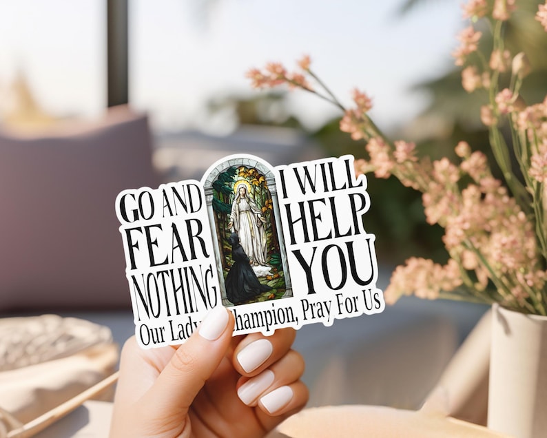 May include: A die-cut sticker featuring a central stained-glass style illustration of a figure in white robes standing before a kneeling person. The text reads: GO AND FEAR NOTHING I WILL HELP YOU Our Lady of Champion, Pray For Us in black font.
