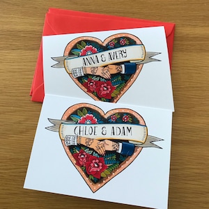 Two white cards with a red envelope. Each card has a heart-shaped design with a couple's names and a banner. The first card has the names 'Anna & Avery' and the second card has the names 'Chloe & Adam'.