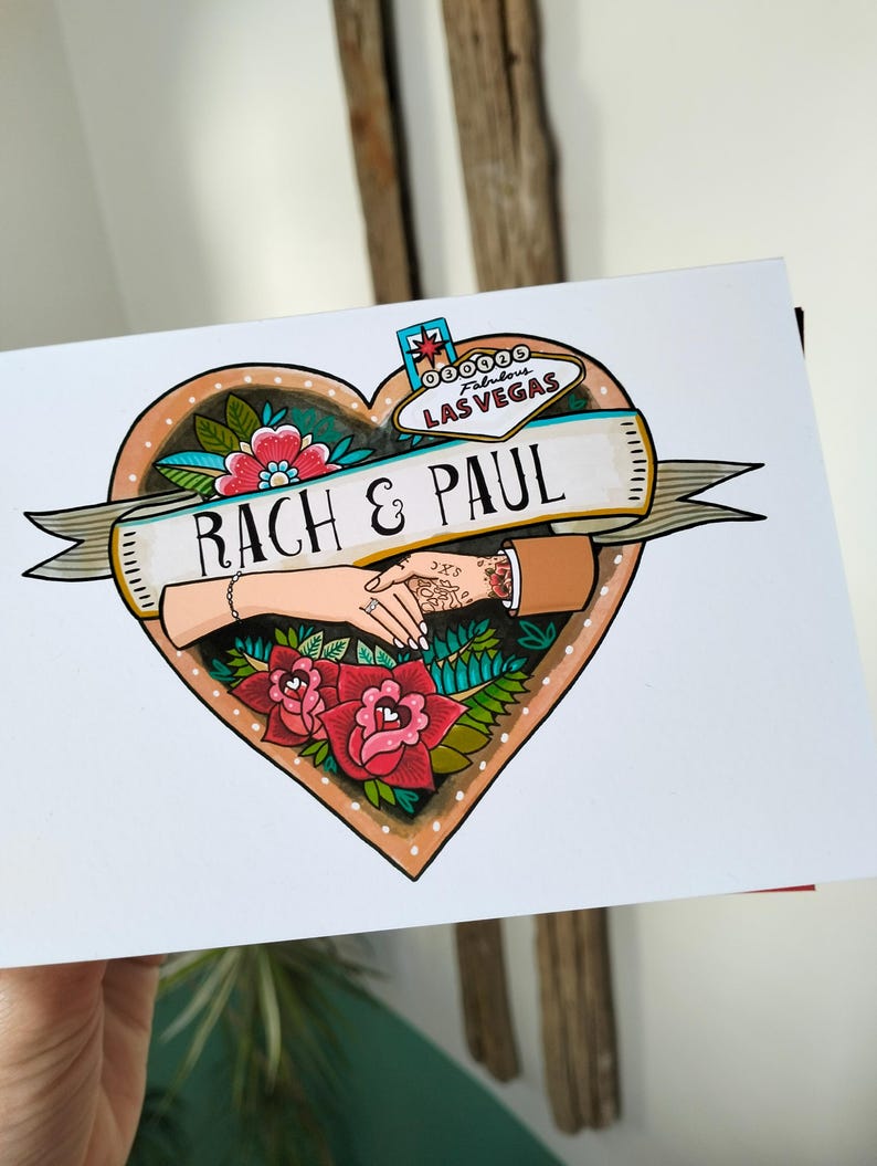 May include: A rectangular greeting card featuring a heart-shaped illustration with a Las Vegas sign at the top. A banner across the center reads RACH & PAUL. The design includes two hands holding each other, surrounded by red and pink flowers and green leaves.