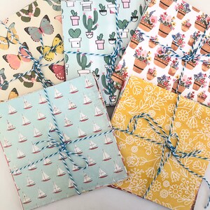 May include: Five different patterned paper squares tied together with twine. The patterns include sailboats, cacti, flowers, and a floral design.