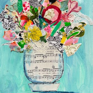 May include: Mixed media artwork of a vase filled with colorful paper flowers and greenery. The vase is made from sheet music and sits on a white base. The background is a light teal color. Text on the vase reads "she wants to dance".