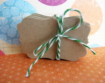 May include: A stack of brown, scalloped gift tags tied together with green and white twine.