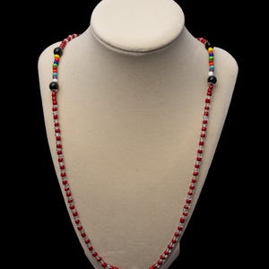 May include: A red and clear beaded necklace with black and white beads at the center.