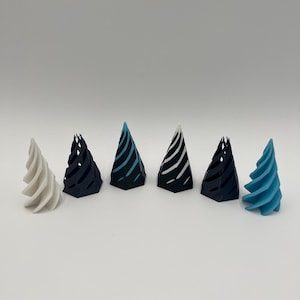 May include: A collection of six decorative, cone-shaped objects. The objects are in various colors, including white, black, and blue. Some have striped patterns. The objects are arranged in a row against a white background. The objects appear to be 3D printed.