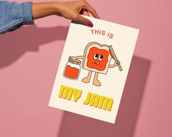 May include: A white card with a cartoon illustration of a slice of bread with a face holding a jar of jam and a knife. The text "This is my jam" is written in yellow letters on the card.
