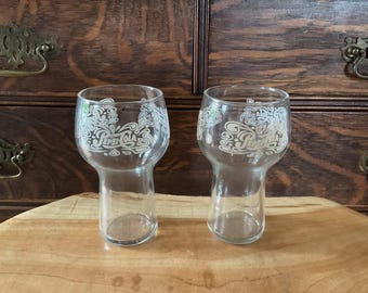 May include: Two clear glass Pepsi Cola glasses with a white swirl design and the Pepsi Cola logo.