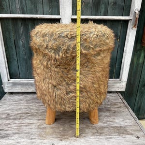 Pu&ograve; includere: Uno sgabello in finta pelliccia marrone e nera con gambe in legno. Lo sgabello &egrave; alto 43 cm.