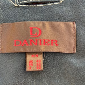May include: A brown leather jacket with a label that reads "D. Danier" and size information: M/M, UK 40, FR 50, IT 50.