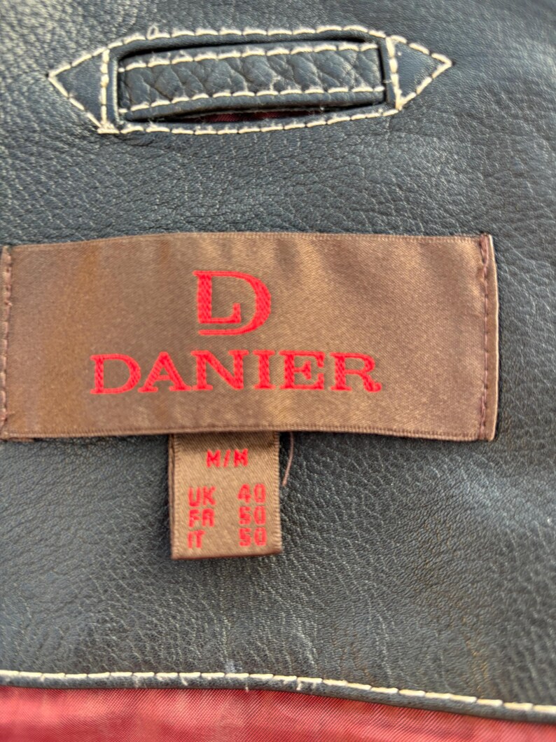 May include: A brown leather jacket with a label that reads "D. Danier" and size information: M/M, UK 40, FR 50, IT 50.