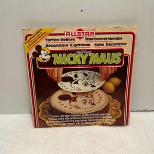 May include: A vintage Mickey Mouse cake decorating kit with stencils for Mickey and Minnie Mouse. The box features a photo of a cake decorated with the stencils and the text "Walt Disney's Mickey Mouse".
