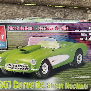 May include: A model kit box for a 1957 Corvette Street Machine. The box is green, white and black with a picture of the car on the front. The text on the box reads "1957 Corvette Street Machine" and "Street Customs Sp&eacute;ciaux de ville".
