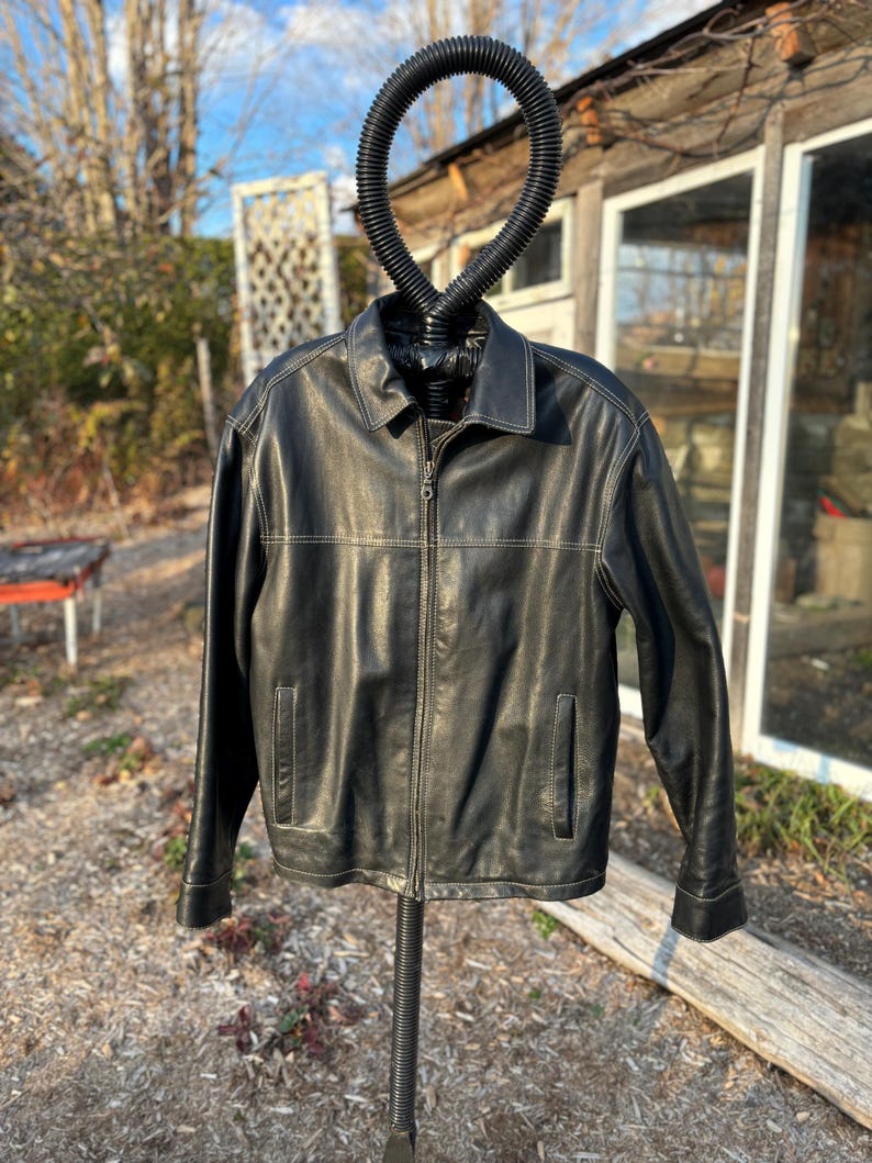 May include: A black leather jacket with a zipper closure and a stand-up collar. The jacket has a light brown stitching detail.