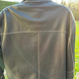 May include: A black leather jacket with white stitching. The jacket has a collar and a button closure.