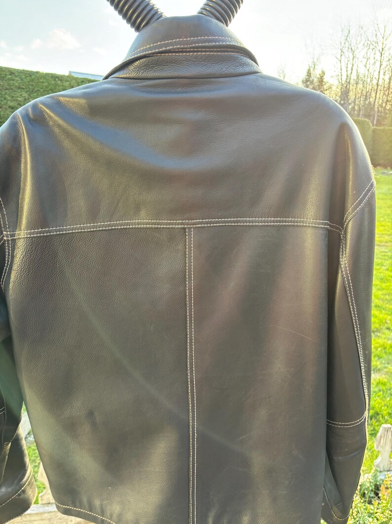 May include: A black leather jacket with white stitching. The jacket has a collar and a button closure.