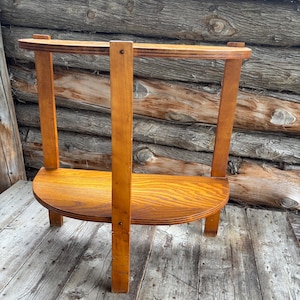 May include: A wooden, semi-circular shelf with two vertical supports and a curved top rail. The shelf is made of light-coloured wood and is set against a weathered wood background. The shelf is approximately 61 cm wide and 30 cm deep.