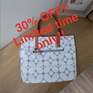 May include: A tote bag featuring a white floral pattern on a tan background, brown leather-like handles attached with silver rivets, and a horizontal zippered pocket on the front. The text 30% OFF!! Limited time only!! is overlaid on the image.