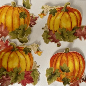 May include: Four orange pumpkins with green leaves and red and brown fall leaves. The pumpkins are arranged in a square pattern on a white background.
