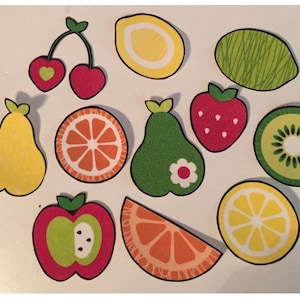 May include: A collection of colorful, paper fruit cutouts. The assortment includes cherries, lemons, a lime, a strawberry, a kiwi, pears, an apple, and orange slices. Each fruit has a black outline and decorative details.