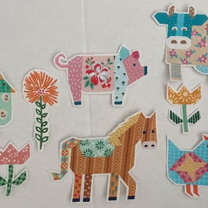 Könnte beinhalten: Eine Sammlung von Stoffaufnähern mit Bauernhoftieren und Blumen. Die Aufnäher umfassen eine Kuh, ein Schwein, ein Pferd und zwei Hühner sowie mehrere Blumen. Die Aufnäher sind farbenfroh und haben florale Muster.