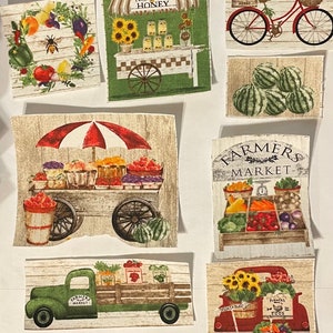May include: A collection of fabric squares featuring various images related to a farmer's market. The squares include a red truck with sunflowers, a green truck with vegetables, a cart with produce, a honey stand, a bicycle with a basket of produce, and a sign that says "Farmers Market".
