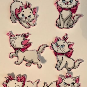 Może przedstawiać: Sześć białych naszywek z kotami z różowymi akcentami. Każdy kot ma różową kokardę i uszy oraz niebieskie oczy. Koty są przedstawione w różnych pozach. Naszywki są prawdopodobnie przeznaczone do odzieży lub rękodzieła.