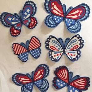 May include: Five fabric butterfly appliques in red, white, and blue patriotic colors. The butterflies have a variety of patterns, including stars and stripes.