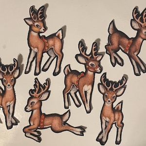 May include: Seven brown and white reindeer cutouts with black outlines. Each reindeer has large antlers and a red and gold harness. Some are standing, while others are in motion, creating a festive holiday theme.