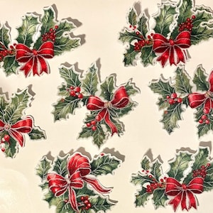 May include: Seven die-cut paper embellishments featuring illustrations of green holly leaves, clusters of small red berries, and bright red bows with white highlights. Each piece is shaped to follow the contours of the holly and ribbon design.