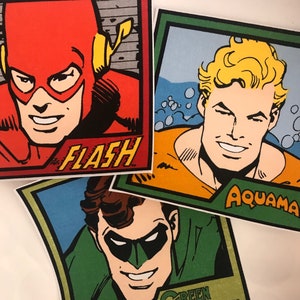 Könnte beinhalten: Drei bunte Comic-Figuren-Illustrationen. The Flash ist rot mit einem gelben Blitz, Aquaman ist orange mit blauem Wasser dahinter und Green Lantern ist grün mit einer schwarzen Maske.