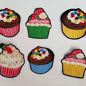 Puede incluir: Seis parches de cupcake de fieltro coloridos con diferentes glaseados y chispas. Los cupcakes son de diferentes colores, incluyendo rosa, verde, amarillo y marrón.