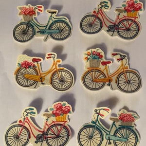 May include: A collection of six decorative bicycle cutouts. Each bicycle is a different color, including teal, red, and yellow, and features a basket filled with flowers. The bicycles have black wheels and are set against a white background.