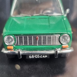 Puede incluir: Un coche verde en miniatura con una parrilla plateada, faros y una matrícula que dice "68-05 CAP". El coche modelo tiene un techo blanco y luces de posición naranjas. Es un modelo vintage.