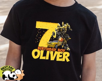 May include: Black t-shirt with a yellow number 7, a yellow car, a yellow robot, and the text "Birthday Boy Oliver".