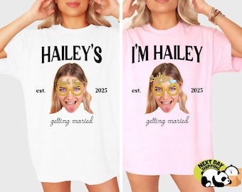 May include: Two white t-shirts with the text "HAILEY'S est. 2025 getting married" and "I'M HAILEY est. 2025 getting married". The shirts feature a bride-to-be face with a bride-to-be headband and glasses.