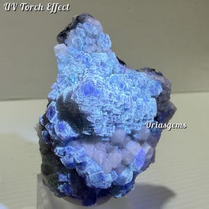 May include: A close-up of a mineral specimen with a UV torch effect. The mineral is a mix of blue and white hues, with a crystalline structure. The text "UV Torch Effect" is at the top left, and "Oriasgems" is at the bottom right.