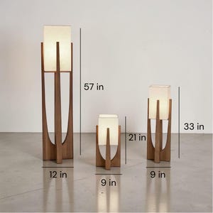 Puede incluir: Tres l&aacute;mparas de madera con pantallas rectangulares de tela. La l&aacute;mpara m&aacute;s alta mide 145 cm de alto y 30 cm de ancho. La l&aacute;mpara mediana mide 84 cm de alto y 23 cm de ancho. La l&aacute;mpara m&aacute;s peque&ntilde;a mide 53 cm de alto y 23 cm de ancho.
