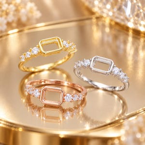 May include: Three metal rings featuring a central rectangular setting for a stone, flanked by three small round clear stones on each side. The set includes one gold-tone ring, one silver-tone ring, and one rose gold-tone ring, all with polished bands.