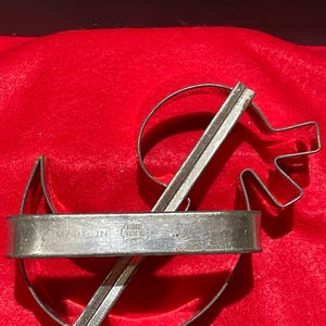Może przedstawiać: Metalowa foremka do ciasteczek w kształcie koguta. Foremka składa się z dwóch części, które pasują do siebie. Foremka jest oznaczona "Made in U.S.A."