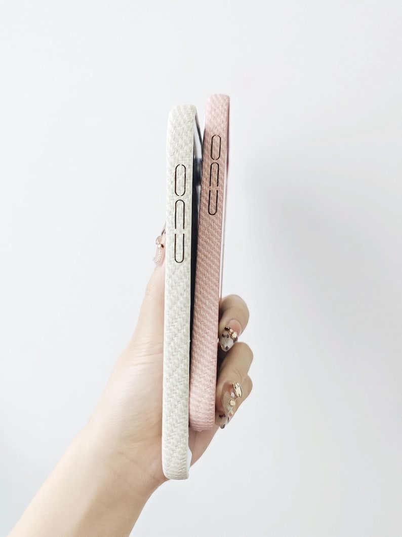 May include: Two rectangular smartphone cases held together, one in a textured off-white finish and the other in a textured light pink finish. Both cases feature precise cutouts for side buttons and a slim, protective profile for mobile devices.