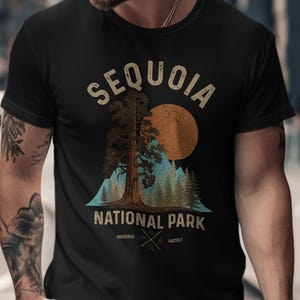 May include: Black t-shirt featuring a Sequoia National Park design. The graphic includes a large tree, a setting sun, and the words "Sequoia National Park". The shirt also has the words "Preserve" and "Protect".