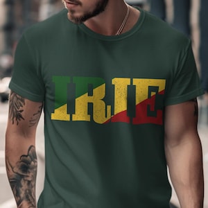 May include: Dark green t-shirt with the word "IRIE" in large, distressed lettering. The letters are colored in green, yellow, and red, reminiscent of a flag. The shirt is a crew neck style.