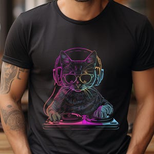 May include: Black t-shirt featuring a neon illustration of a cat wearing sunglasses and headphones, operating a DJ mixer. The cat is outlined in vibrant colors, creating a striking visual effect. The design is centered on the shirt.
