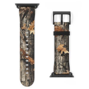May include: A camouflage-style watch strap with a black buckle and connectors. The strap displays a realistic print of tree bark and fallen leaves in shades of brown, tan, and green. The watch strap is designed to fit a smartwatch.