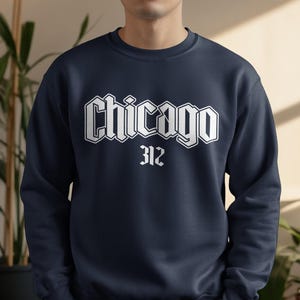 May include: Navy blue sweatshirt with the word "Chicago" in a white gothic font and the number "312" below it. The sweatshirt is a crew neck style.