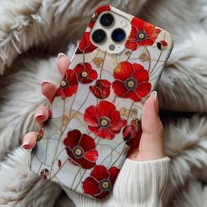 May include: A white iPhone case with a floral design featuring red poppies. The case has a clear back and a white border around the camera lens.