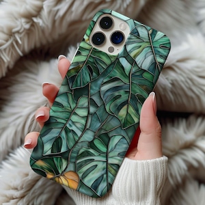 Puede incluir: Una funda de teléfono verde y dorada con un diseño de hojas tropicales en vitral.