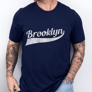 May include: A navy blue t-shirt with a white vintage-style graphic that says "Brooklyn".